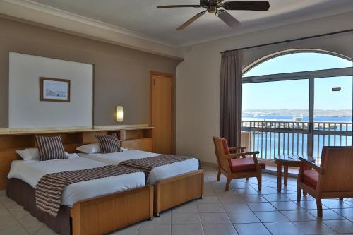 a hotel room with two beds and a balcony at Paradise Bay Resort in Mellieħa