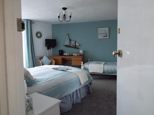 a bedroom with two beds and a desk with a television at Corner House Guest House in Bideford