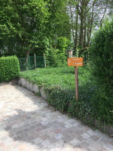 a brown sign in front of a hedge at 't Huizeke in Asse