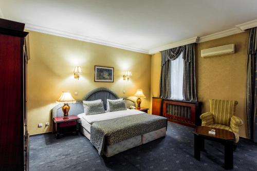 Habitación de hotel con cama y silla en Ambassador, en Almaty