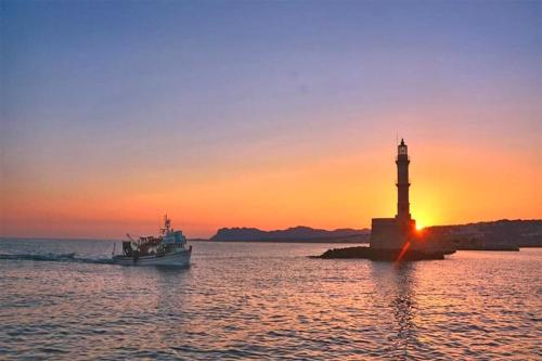 a boat in the water next to a lighthouse at Pozzi Di Lusso Suites in Chania Town