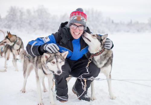 a man with two husky dogs in the snow at Aurora Village Ivalo in Ivalo