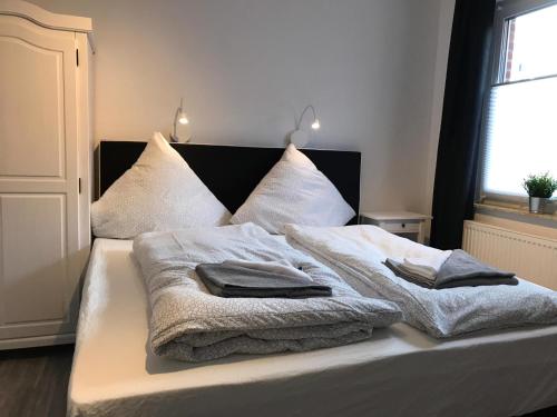 Una cama con mantas blancas y almohadas. en Kleine Möwe en Neßmersiel