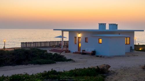 a small white house on the beach at sunset at Magoito1 in Sintra