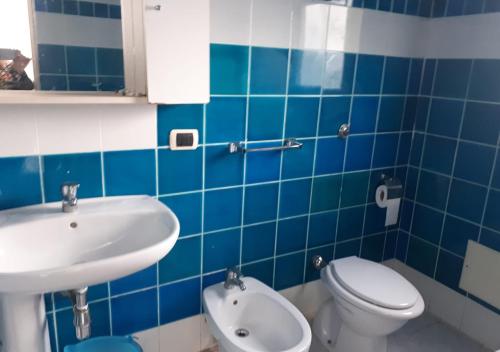 bagno piastrellato blu con servizi igienici e lavandino di GALLURAS B&B a Olbia