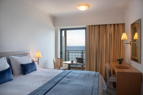 a hotel room with a bed and a desk and a window at Chios Chandris in Chios