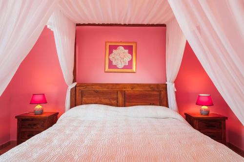 a bedroom with pink walls and a bed with two lamps at Solemar Sicilia - Casa Enza in Santa Flavia