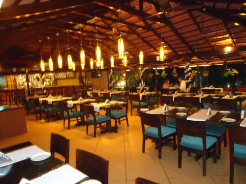 a dining room with tables and chairs and chandeliers at Colonia Santa Maria in Baga