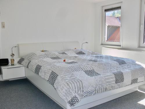 een wit bed met een zwart-wit dekbed en een raam bij Ferienwohnung Sagenhaft in Bad Harzburg
