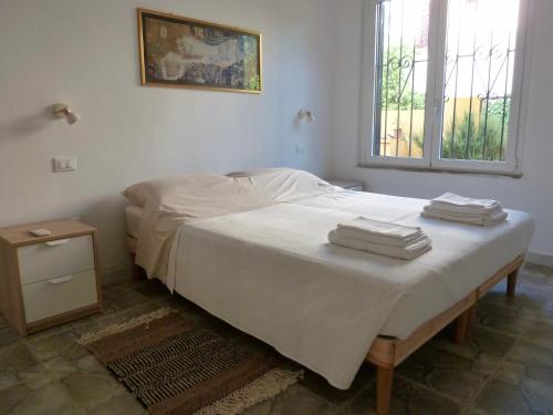 a bedroom with a bed with white sheets and a window at Villa Asmara in Su Forti