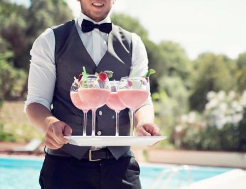 a man holding a tray with three champagne glasses at Hotel Garden Riviera in Santa Maria di Castellabate