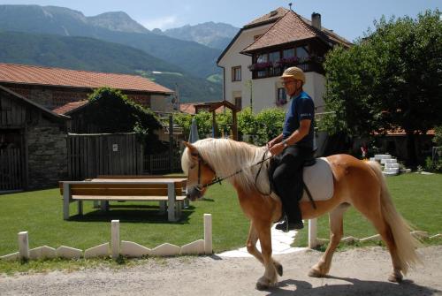 a man riding on a horse in front of a house at Landhotel Anna in Silandro