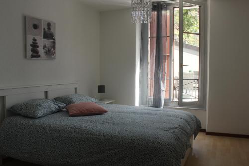 a bedroom with a bed and a window with a chandelier at Appartement rénové Montreux 2-8 personnes in Montreux