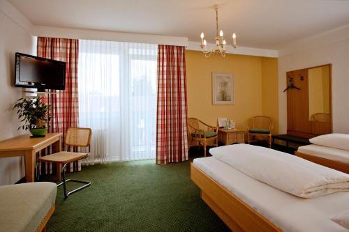 a hotel room with two beds and a television at Hotel Mayer in Germering