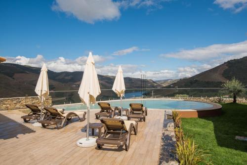 a patio with chairs and umbrellas next to a pool at Vila Gale Douro Vineyards in Armamar