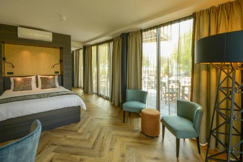 een hotelkamer met een bed, stoelen en ramen bij Boutique Hotel Karel de Stoute in Gorinchem