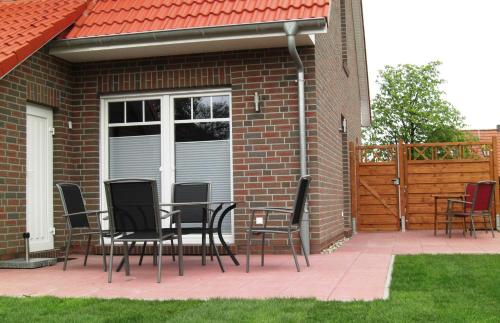 een patio met stoelen en een tafel voor een huis bij Ferienhaus Wattwurm Neu in Hooksiel