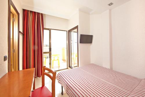 a bedroom with a bed and a table and a window at MLL Caribbean Bay in El Arenal