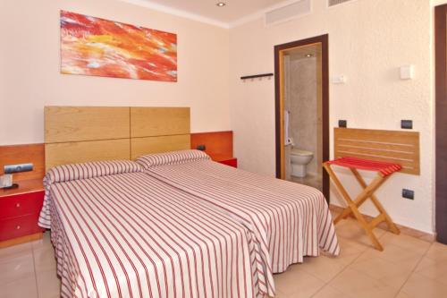 a bedroom with a bed with a striped blanket at MLL Caribbean Bay in El Arenal
