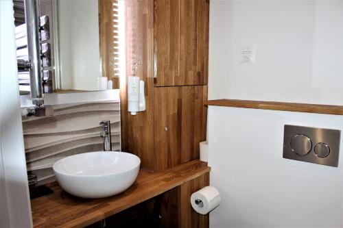 a bathroom with a white bowl sink on a wooden counter at RIOSHOUSE George-Inn in Gerrards Cross