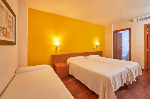 a room with two beds and a yellow wall at MLL Blue Bay in Palma de Mallorca