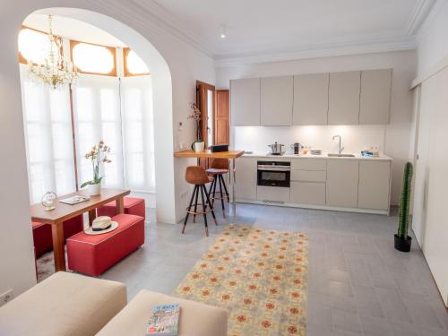 una cucina con armadi bianchi e un divano rosso di Es Palauet Brandnew one suite apartment in Ibiza center a Ibiza Città