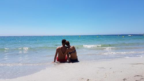 two people sitting on the beach looking at the ocean at Guilvinec Parc Residence in Le Guilvinec