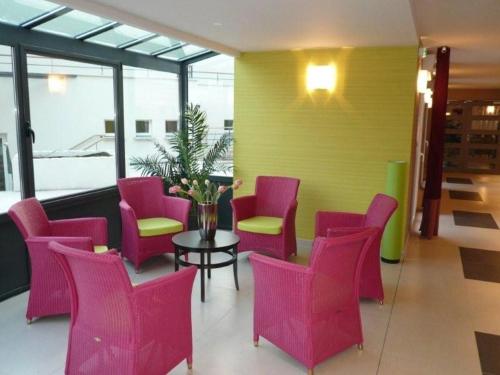 a lobby with pink chairs and a table and a yellow wall at Guilvinec Parc Residence in Le Guilvinec