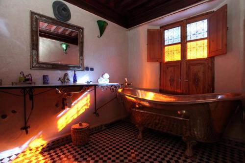a bathroom with an old tub and a window at Riad Tahar Oasis in Marrakesh