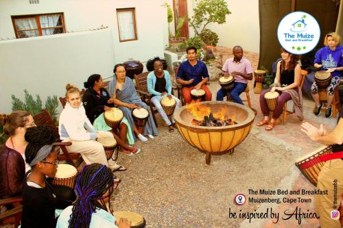 a group of people sitting around a fire pit at The Muize in Muizenberg
