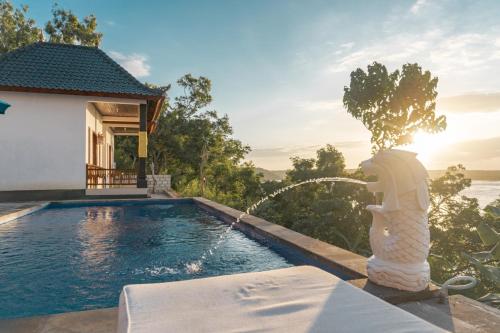 una piscina accanto a una casa con fontana di Prasi Sunset Bungalows a Nusa Penida