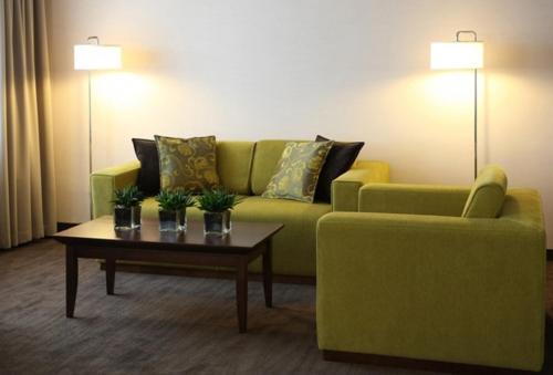 a living room with a green couch and a coffee table at Mercure Marijampole in Marijampolė