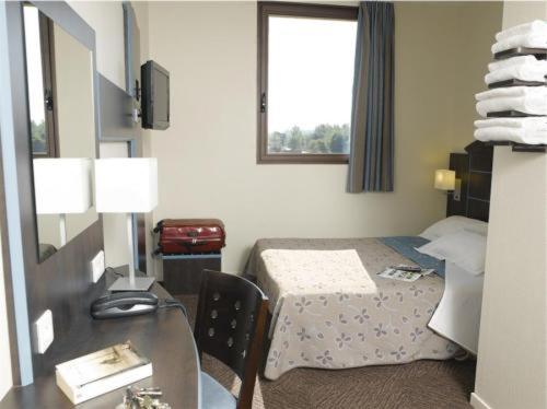 Habitación de hotel con cama, mesa y escritorio. en Hôtel Akena City Albi Gaillac en Brens