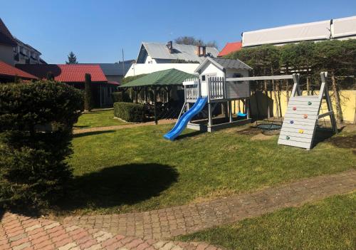 un parque infantil con un tobogán en un patio en Domki Letniskowe Bartek, en Rewal