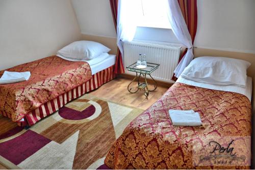 a room with two beds and a table with a window at U Schabińskiej - Jedzenie i Spanie w Jaśle in Jasło