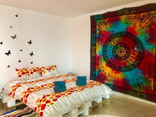 Habitación con cama y una gran pintura en la pared. en Finca Arcoíris Tenerife VV, en Guía de Isora