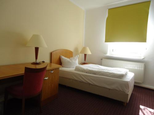a hotel room with a bed and a desk and a window at Hotel Schweizer Hof in Halle an der Saale