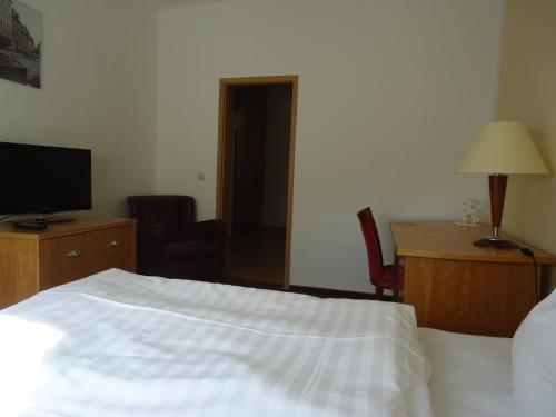 a bedroom with a bed and a desk and a television at Hotel Schweizer Hof in Halle an der Saale