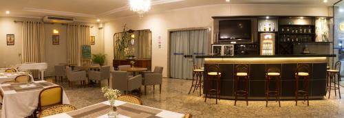 a restaurant with a bar and some tables and chairs at Hotel Dan Inn Franca & Convenções By Nacional Inn in Franca