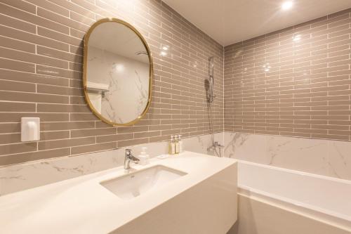 a bathroom with a sink and a mirror and a tub at Brown Dot Gijang Yeonhwari in Busan
