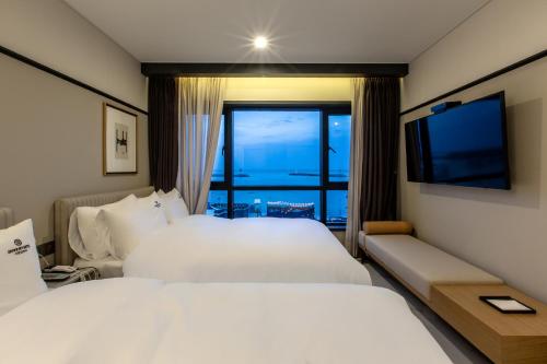 a hotel room with two beds and a television at Brown Dot Gijang Yeonhwari in Busan