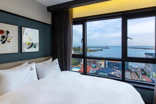 a bedroom with a bed and a large window at Brown Dot Gijang Yeonhwari in Busan