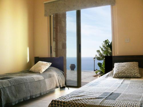 a bedroom with two beds and a view of the ocean at Happy Trails Pomos Panoramic Villa in Pomos