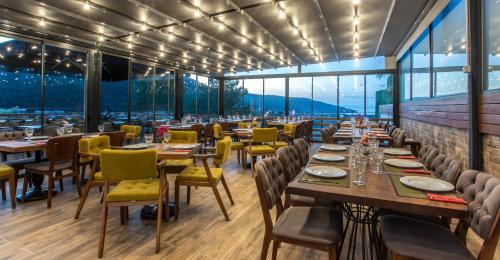 een restaurant met tafels en stoelen en grote ramen bij Alya Sierra Villa Hotel in Mugla