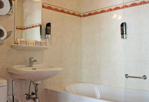 een badkamer met een wastafel, een bad en een toilet bij Hotel Prins Hendrik in Amsterdam
