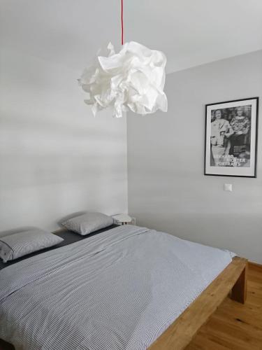 a white bedroom with a bed and a chandelier at Appartamento Fidanza in Brissago
