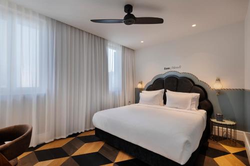 a bedroom with a large white bed with a ceiling at Sam&Blondi in Tel Aviv