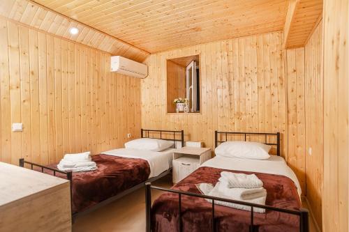 two beds in a room with wooden walls at HOME 6 in Tbilisi City
