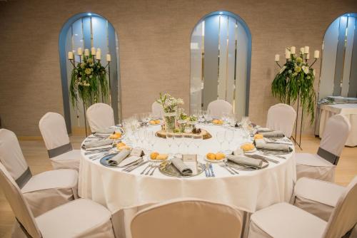 a table in a room with white chairs and a table with food at Hotel Olympia Valencia in Alboraya