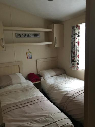 a room with two beds and a sign that reads this is our money fake at Take me to the beach at J&S caravan holidays Newquay Bay resort in Saint Columb Minor